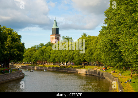 Menschen entspannen Sie sich an den Ufern des Flusses Aura (Aurajoki), Turku Finnland mit dem Dom-Turm auf die skyline Stockfoto