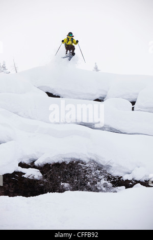 Eine Skifahrerin, von einer Klippe zu springen an einem stürmischen Tag in Colorado. Stockfoto