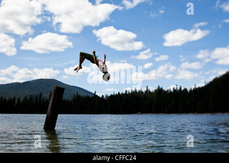 Ein junger Mann Backflipping an einem Pier an einem See in Idaho. Stockfoto