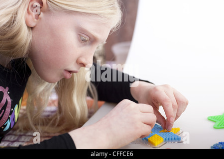 Kleines blondes Mädchen mit Hama-Perlen zu spielen Stockfoto