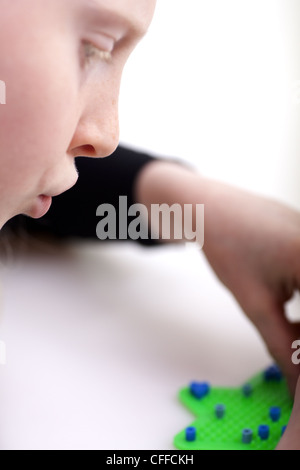 Kleines blondes Mädchen mit Hama-Perlen zu spielen Stockfoto