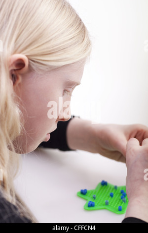 Kleines blondes Mädchen mit Hama-Perlen zu spielen Stockfoto