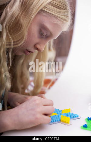 Kleines blondes Mädchen mit Hama-Perlen zu spielen Stockfoto