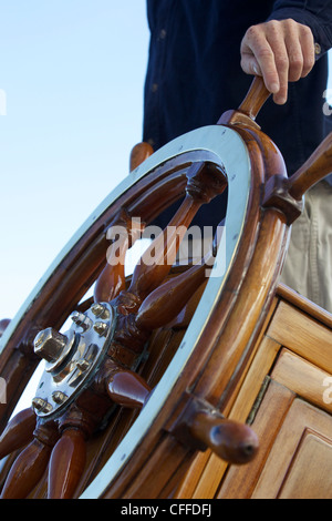 Der Kapitän hält seine Hand am Steuerrad an Bord der Segelyacht Stockfoto