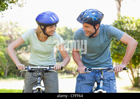Lächelnde paar auf ihren Bikes beim Tragen von Helmen Stockfoto
