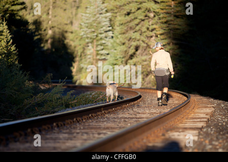 Eine Frau und ihr Hund spazieren einige Gleise auf ihre nächsten Angelplatz. Stockfoto