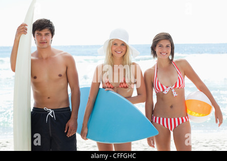 Mann und zwei Frauen auf der Suche nach vorne mit Surfbrettern und lächelnd Stockfoto