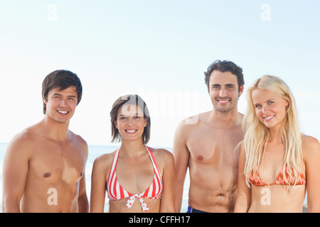 Vier Freunde, Lächeln, als sie nebeneinander stehen Stockfoto