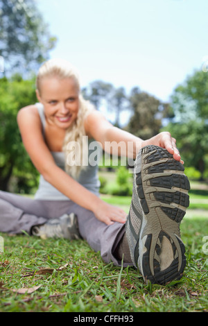 Sportlerin tut ihr erstreckt sich auf dem Rasen Stockfoto