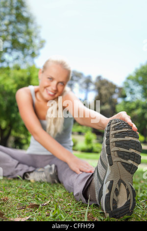 Sportlerin tut erstreckt sich auf dem Rasen Stockfoto