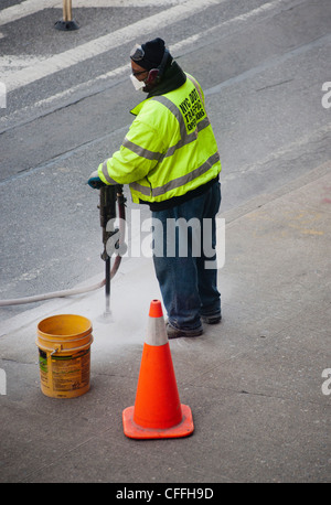 New York City Department of Transportation Arbeiter verwendet einen Presslufthammer um zu brechen, eine konkrete Bürgersteig für ein Ersatz-Zeichen-Projekt Stockfoto