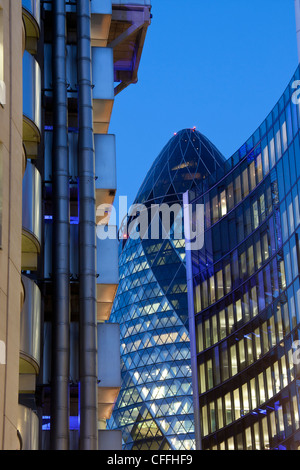 Swiss Re Gebäude 30 St Mary Axe auch bekannt als die Gurke in der Nacht gesehen zwischen Lloyds und Willis Gebäude London England UK Stockfoto