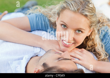 Lächelnde Frau liegt auf ihrem Freund auf dem Rasen Stockfoto