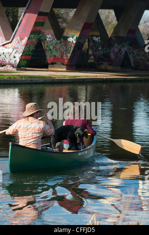 Zwei Personen und ein Hund Kanu fahren Sie unter der A 14 Brücke auf dem Fluss Cam. Cambridgeshire. England. Stockfoto