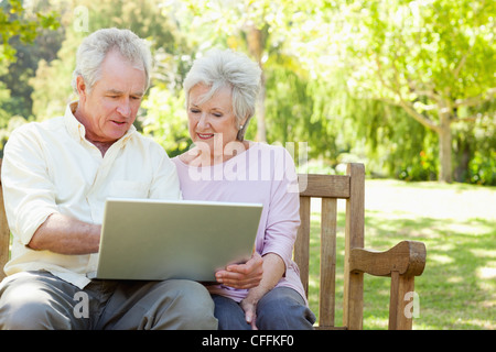 Zwei Freunde Blick auf einem Laptop sitzen nebeneinander auf einer Bank Stockfoto