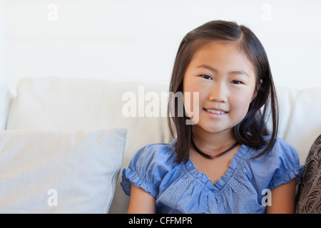 Porträtaufnahme, Mädchen sitzen auf der Couch lächelnd Stockfoto