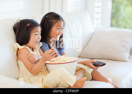 Seitenansicht der beiden Schwestern vor dem Fernseher und Essen popcorn Stockfoto