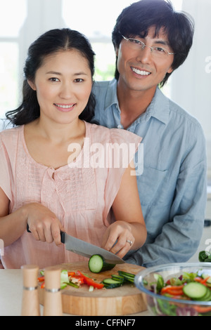 Ein Ehemann seine Frau zu umarmen, wie sie Abendessen in der Küche bereitet Stockfoto