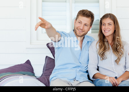 Mann und Frau sitzen auf dem Stuhl außerhalb als der Mann zeigt auf etwas Stockfoto