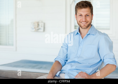 Lächelnd Mann sitzt draußen auf der Veranda Stockfoto