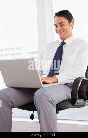 Lächelnde Geschäftsmann mit einem Laptop auf den Knien Stockfoto