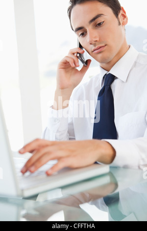 Geschäftsmann mit einem Smartphone während der Eingabe seinen laptop Stockfoto