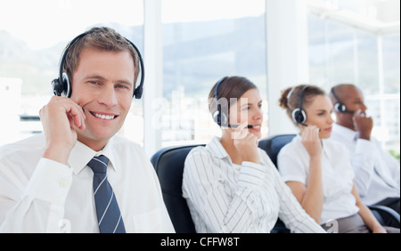 Telefon-Hilfe-Desk-Mitarbeiter sitzt neben seinem Kollegen lächelnd Stockfoto