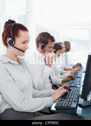 Arbeitende Call-Center-Mitarbeiter sitzen in einer Linie Stockfoto