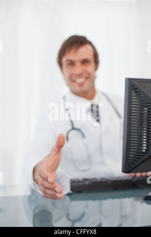 Lächelnde Arzt mit seiner Hand streckte für ein Händedruck Stockfoto