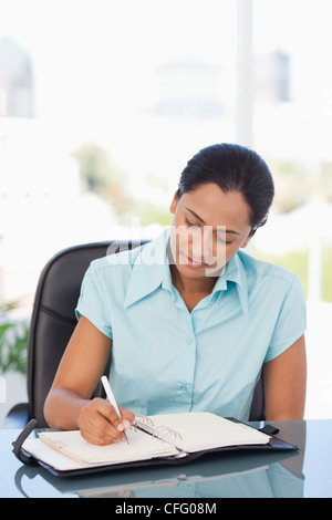 Entspannte Sekretär beim Sitzen am Schreibtisch für ihr Ringbuch Ordner schreiben Stockfoto