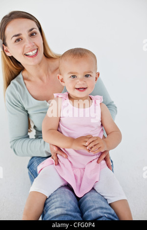 Lächelnde Mutter sitzen halten Sie ihr baby Stockfoto