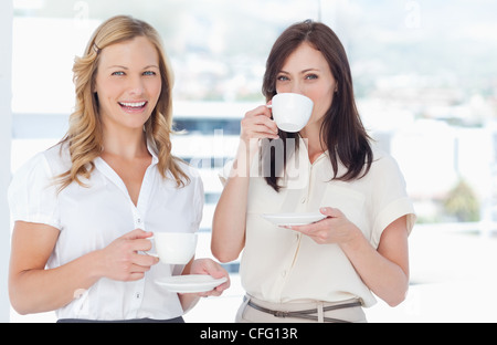 Als sie steht neben ihrer Freundin wer Tee trinkt lächelnde Frau Stockfoto