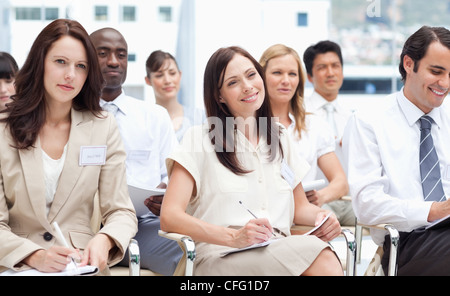 Kollegen, die Lächeln, als sie Notizen schreiben, während Sie sitzen zusammen Stockfoto
