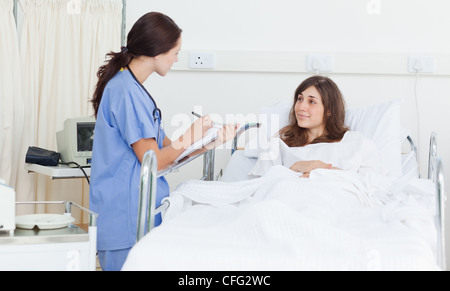 Krankenschwester hält eine Zwischenablage, wie sie ein Gespräch mit einem Patienten hat Stockfoto
