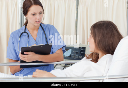 Krankenschwester mit einem Klemmbrett während der Diskussion mit einem Patienten Stockfoto
