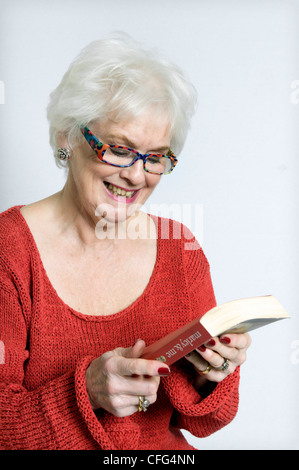 Attraktive ältere Dame in helle Kleidung Lesebuch genommen vor einem weißen Hintergrund Stockfoto