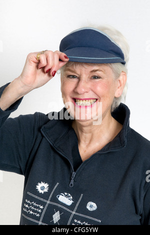 Attraktive senior Dame lächelnd in casual Outdoor Kleidung gegen einen weißen Hintergrund und Holding-Kappe Stockfoto