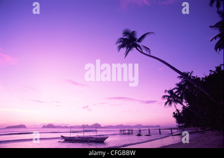 Philippinen, Palawan, Bacuit Bay, El Nido, Ausleger am tropischen Strand bei Sonnenuntergang Stockfoto