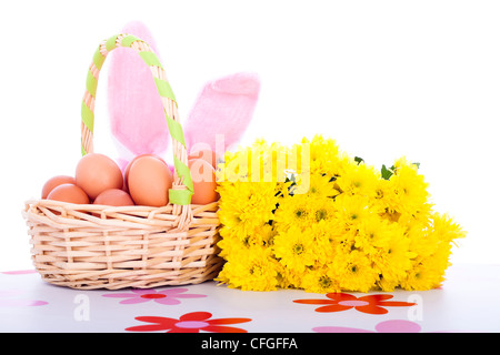 Osterkorb mit Eiern, Blumen und Hasenohren, isoliert auf weißem Hintergrund. Stockfoto