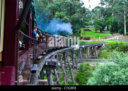 Passagiere auf einem antiken Dampf Zug eine hölzerne Eisenbahnbrücke überquert. Stockfoto