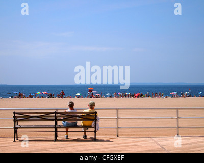 Paar auf Bank mit Blick auf den Strand von Coney Island, New York, USA Stockfoto