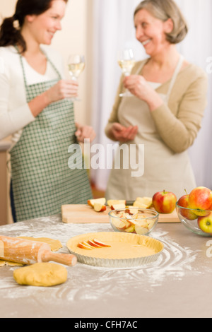 Apfelkuchen backen zwei Frauen trinken Wein zusammen in Küche Stockfoto