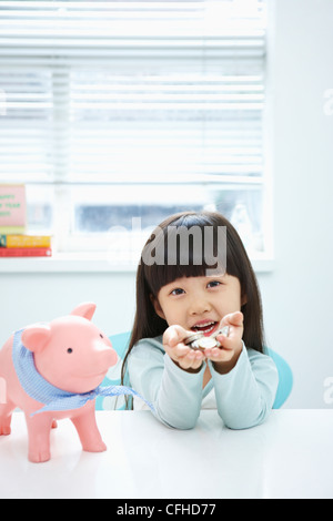 Ein Mädchen in ihren Händen mit einem rosa Sparschwein Münze hält Stockfoto
