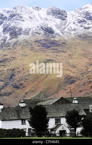 Bauernhaus mit Schnee Langdale Pikes im Hintergrund am Ende des Langdale Valley, Great Langdale, Lake District, Cumbria, England, Großbritannien begrenzt Stockfoto