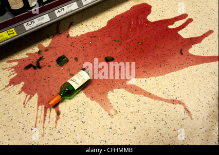Eine Flasche Rotwein, die fallen gelassen wurde und auf dem Boden eines Supermarktes zerschlagen Stockfoto