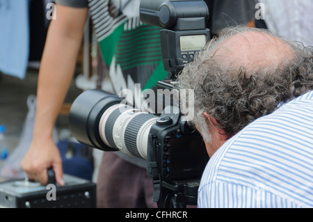 Zurück von einem professionellen männlichen Fotografen mit Glatze und graue Haare schießen eine Canon DSLR mit l Zoom Objektiv - Portrait Stockfoto