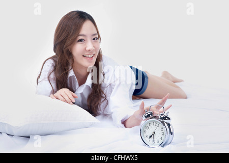 Die Frau, die das Ausschalten der Uhr auf dem Bett Stockfoto