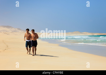 Praia de Chaves, Boa Vista, Kap Verde Inseln. Zwei Männer Joggen entlang der Küstenlinie von langen ruhigen weißen Sandstrand Stockfoto