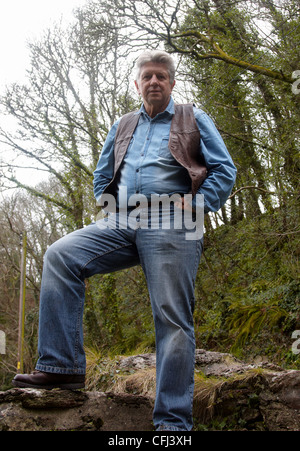 Reifer Mann stehend an einer Wand mit Bäumen im Hintergrund Stockfoto