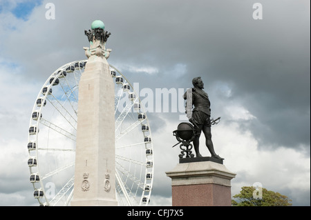 Die Statue von Sir Francis Drake auf Plymouth Hacke mit dem Riesenrad und RAF Kriegerdenkmal dahinter mit einem stürmischen Himmel. Stockfoto